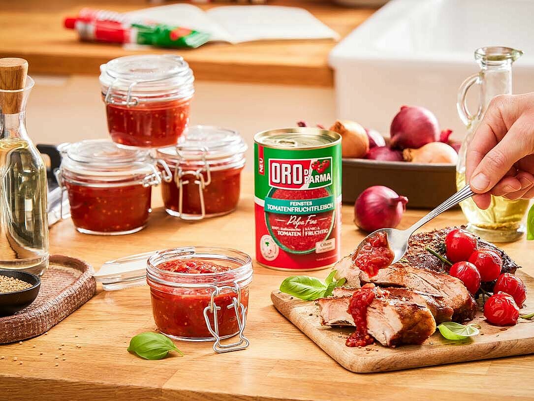 Hand gibt selbstgemachtes Tomaten Chutney über Fleisch